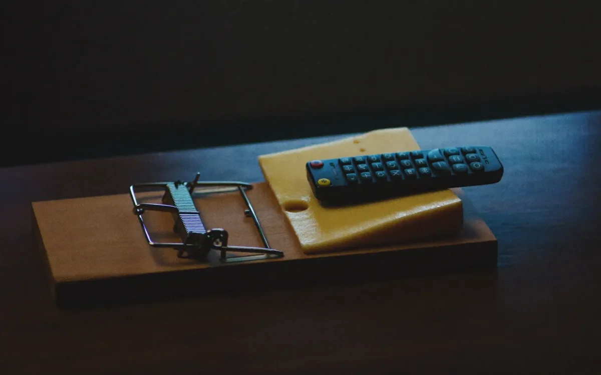 A TV remote resting on cheese in a mousetrap, the hidden catch behind free IPTV in Canada